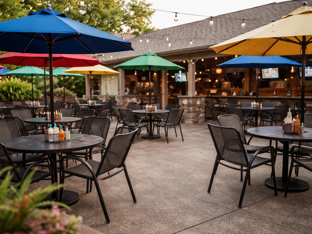 Wide view of a welcoming outdoor patio with colorful umbrellas and empty sports-bar seating.