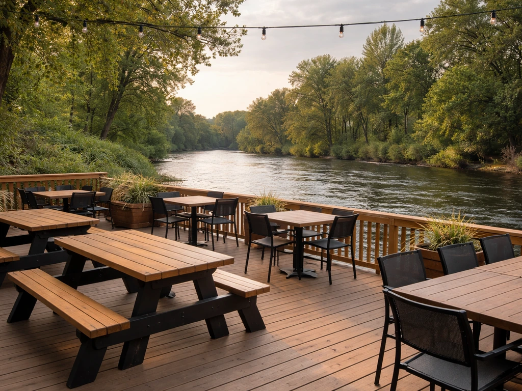 Wide view of The Sandbar patio beside the Boise River greenbelt with outdoor dining chairs and water beyond.